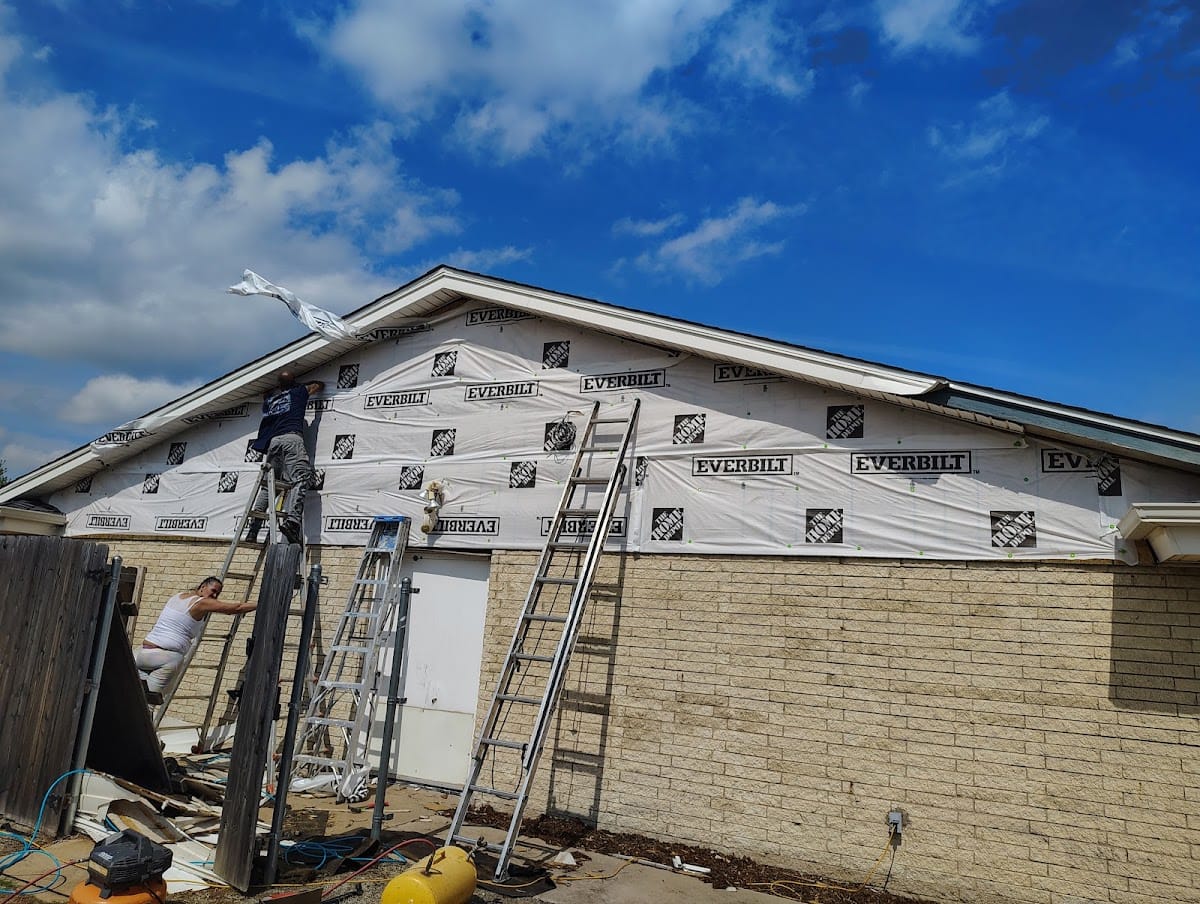 Crew installing house wrap on gable end of brick home