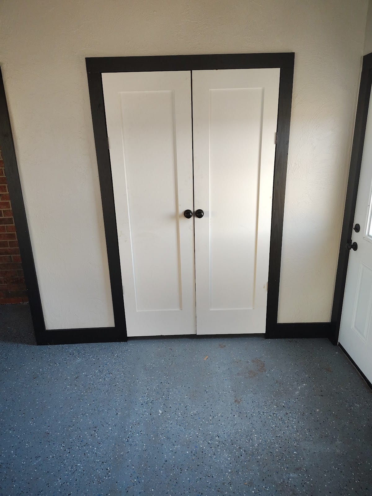 Custom white double doors with dark stained trim and terrazzo floor