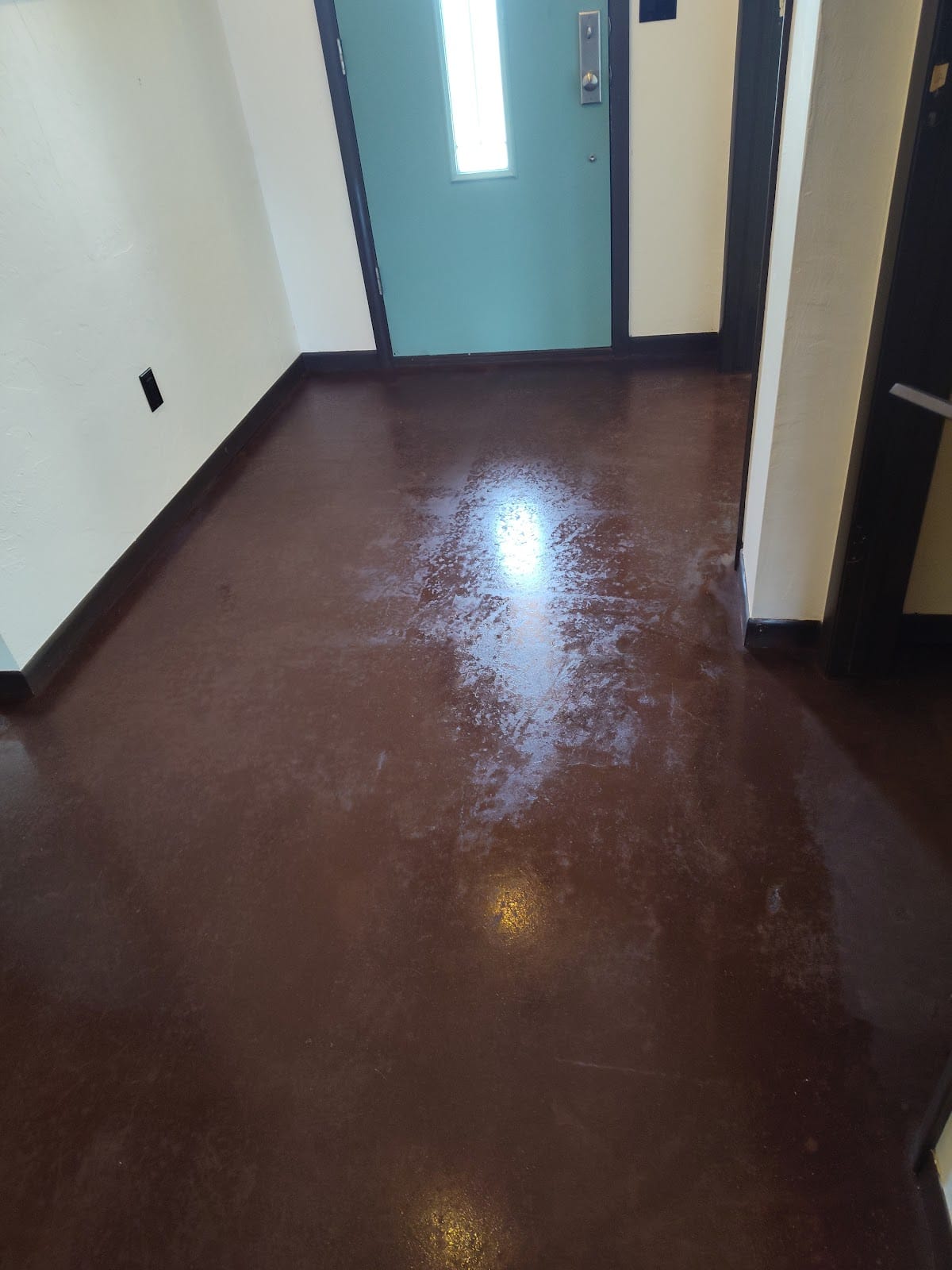 Decorative stained concrete entryway floor with teal painted door