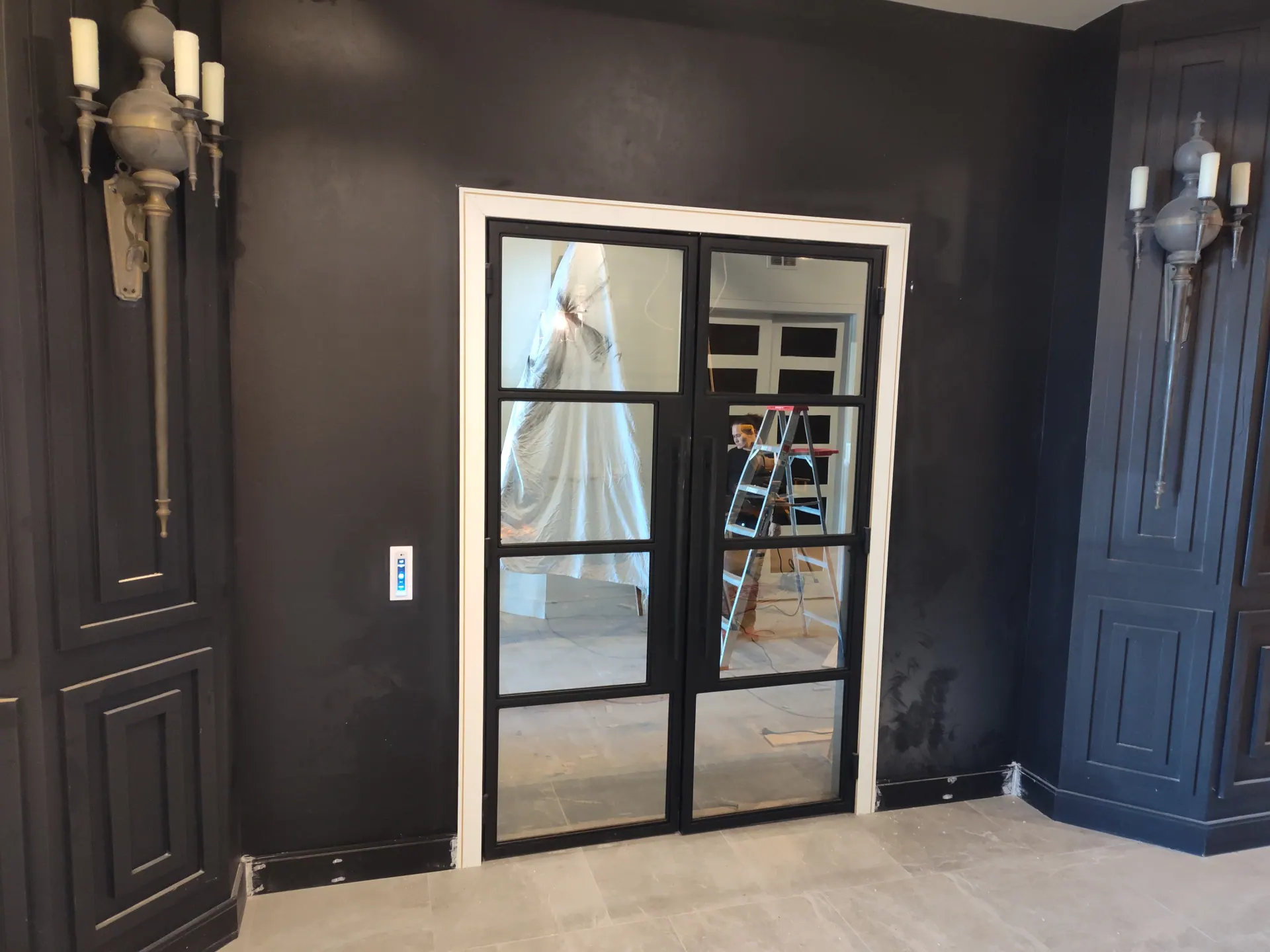 Custom foyer with dark walls and glass-paned double doors