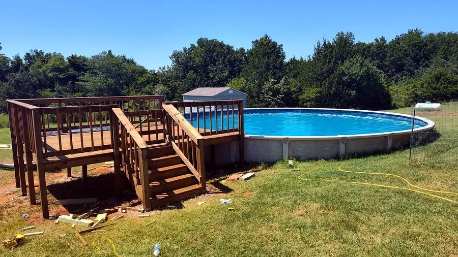 Stained timber deck with railings and steps built around an above-ground pool