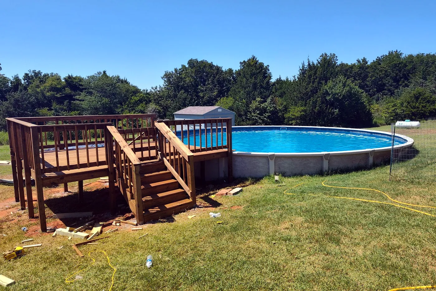 Stained timber deck with railings and steps built around an above-ground pool